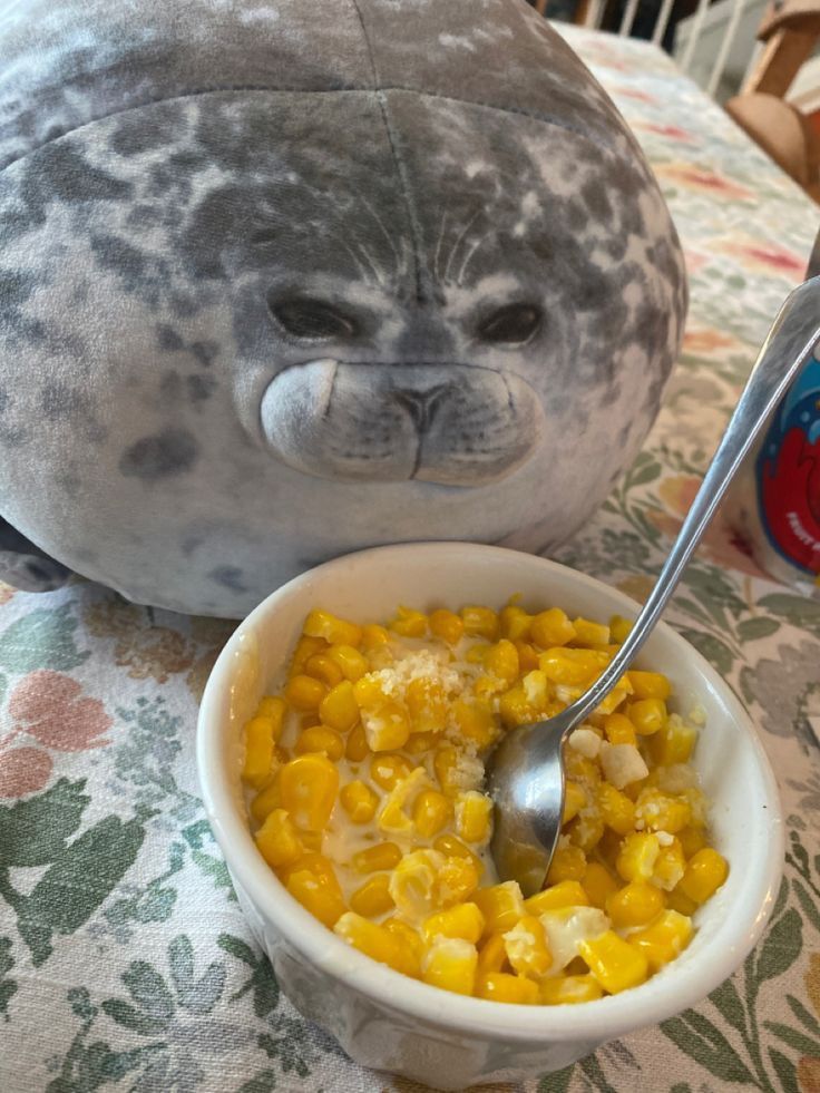 a stuffed seal is next to a bowl of corn