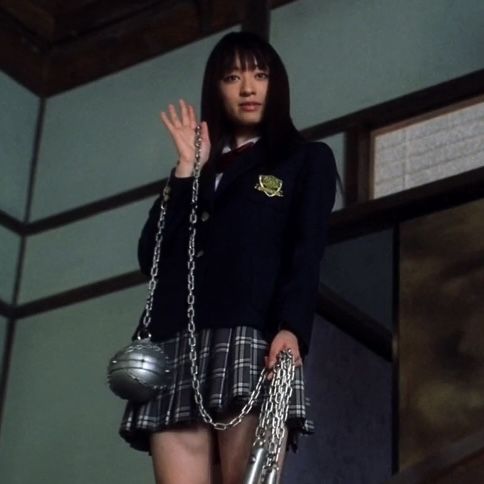 a girl in a school uniform is standing on the stairs with her hand up to her chest