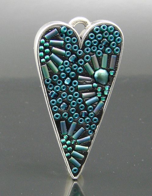 a heart shaped brooch with beads in the shape of a beadwork pattern