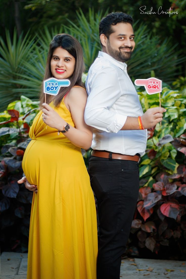 a pregnant couple posing for a photo with signs in front of them that say yes to each other