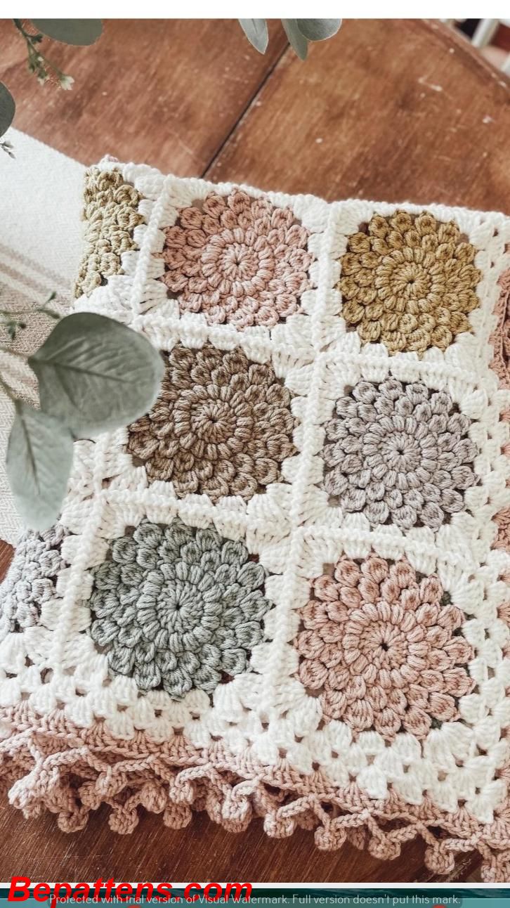 a crocheted blanket is sitting on top of a wooden table next to a potted plant