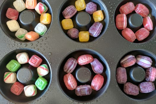 four pans filled with assorted candy sitting on top of a stove burner