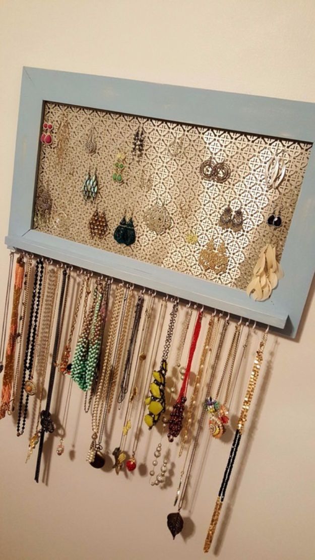 a blue frame with many different necklaces hanging from it's sides and attached to the wall