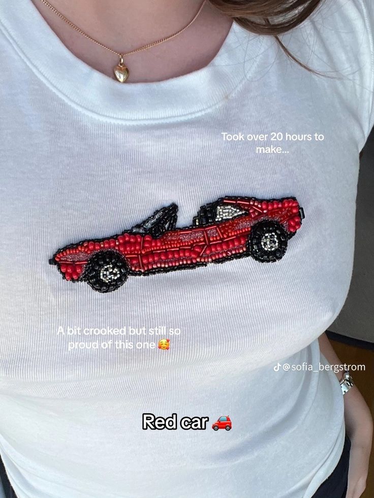 a woman wearing a white shirt with a red car embroidered on it