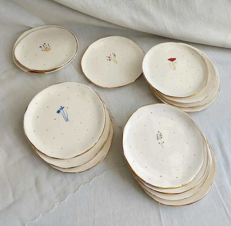 a pile of white plates sitting on top of a table next to a cloth covered bed