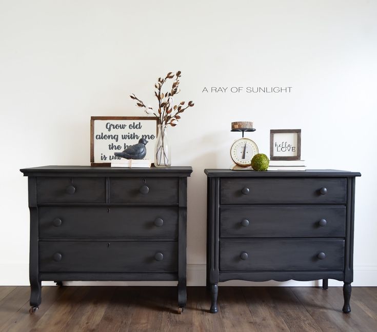 two black dressers sitting next to each other on top of a hard wood floor