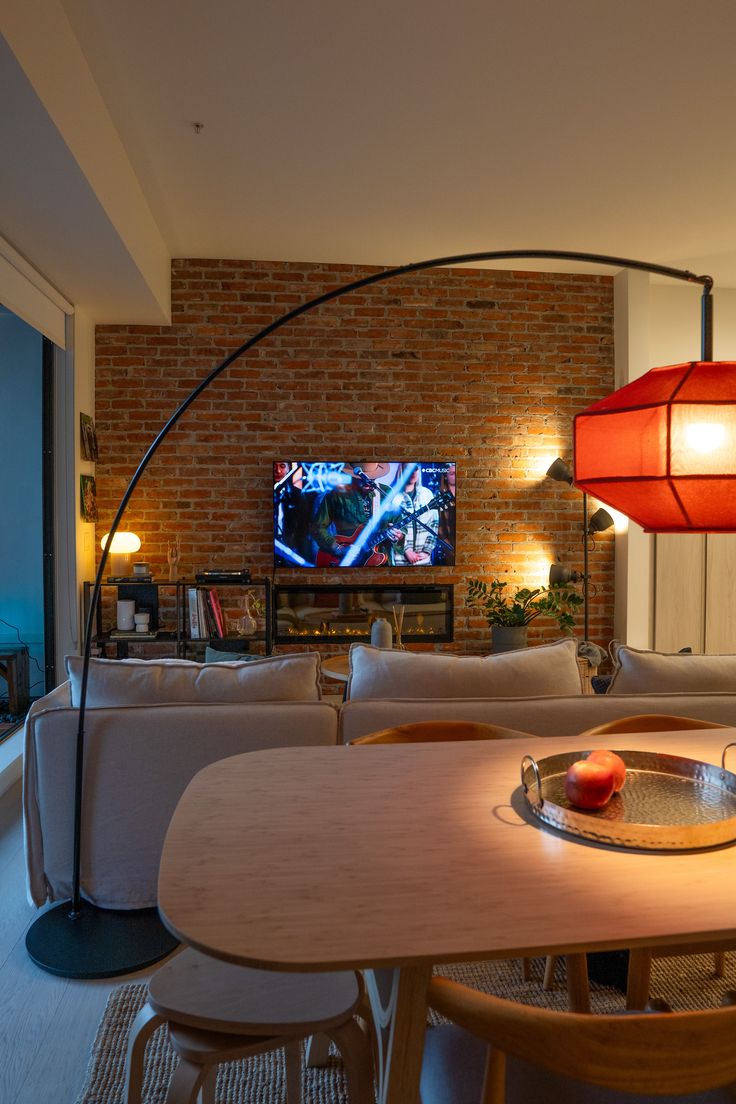 a living room filled with furniture and a flat screen tv mounted to the side of a brick wall