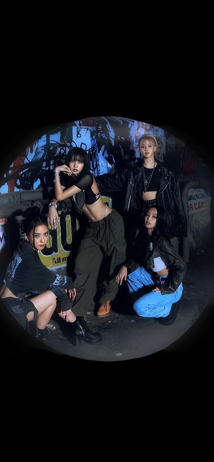 group of young people posing in front of a graffiti covered wall with their arms around each other