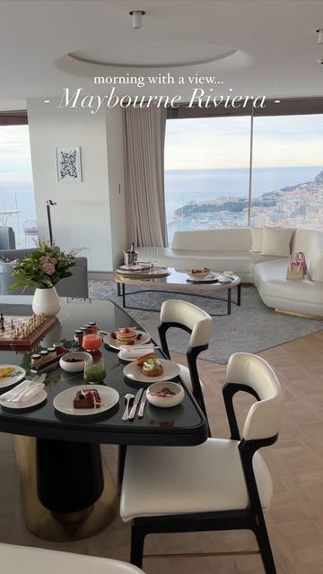 a dining room table with plates of food on it in front of a large window