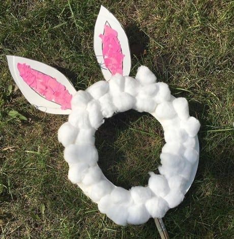 an easter wreath made out of cotton balls and fake bunny ears sitting in the grass