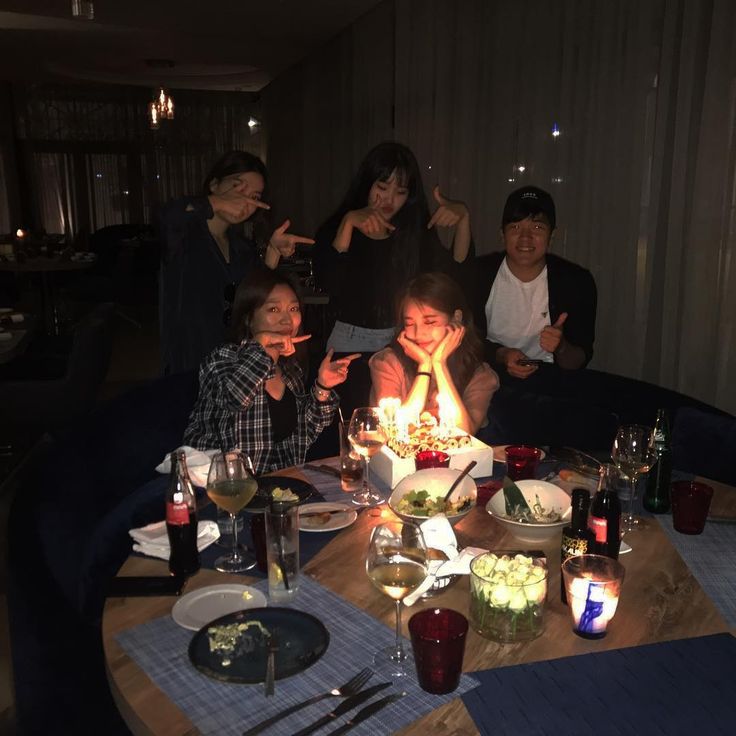 a group of people sitting around a table with a birthday cake on top of it