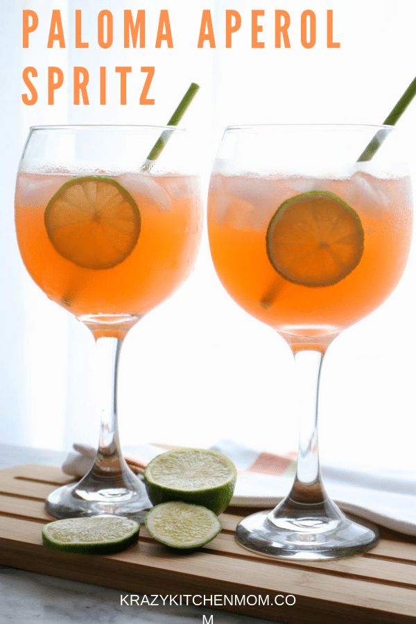 two wine glasses filled with paloma aperol spritz next to sliced cucumbers