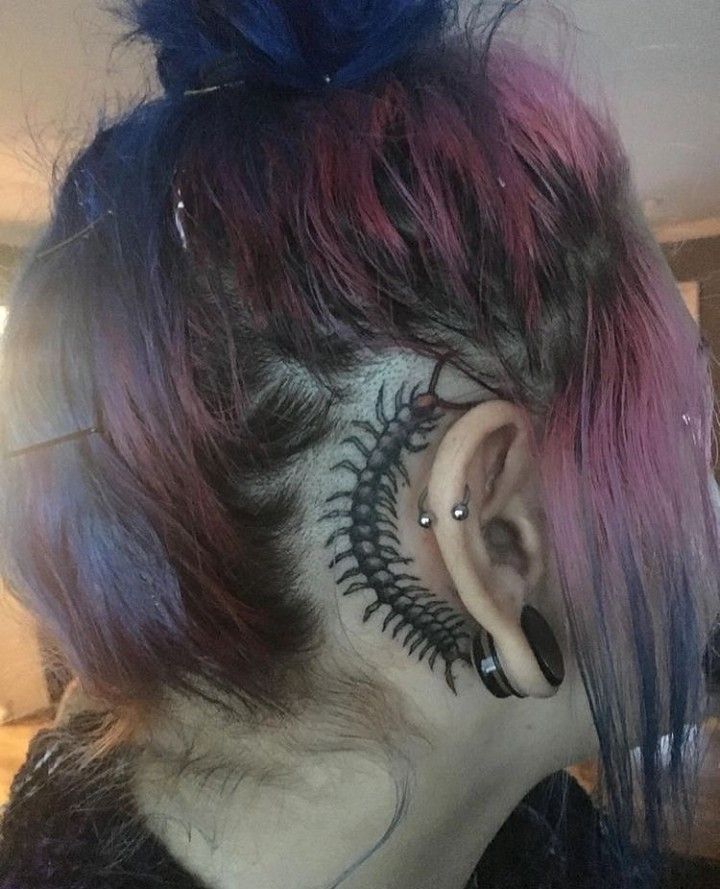 the back of a woman's head with colorful hair and tattoos on her face