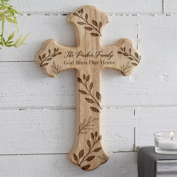 a wooden cross hanging on the side of a white brick wall next to a candle