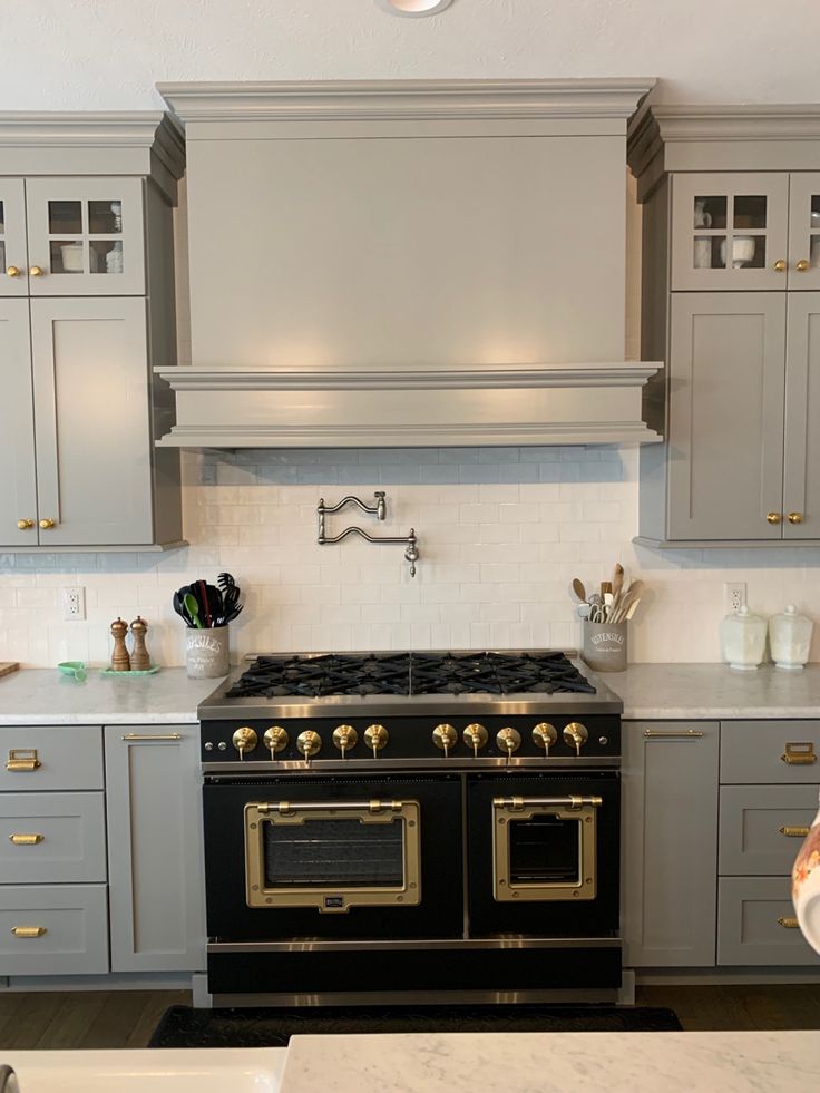 a black and gold stove in a kitchen with white counter tops, gray cabinets and drawers