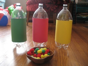 three water bottles sitting on top of a wooden table next to a bowl filled with candy