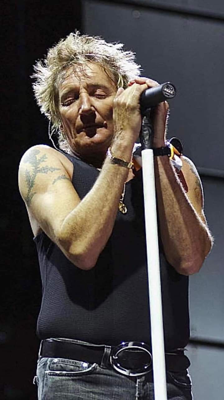 a man holding a microphone up to his face while standing in front of a stage