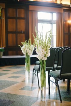 two vases filled with flowers sitting on top of a checkered floor next to chairs