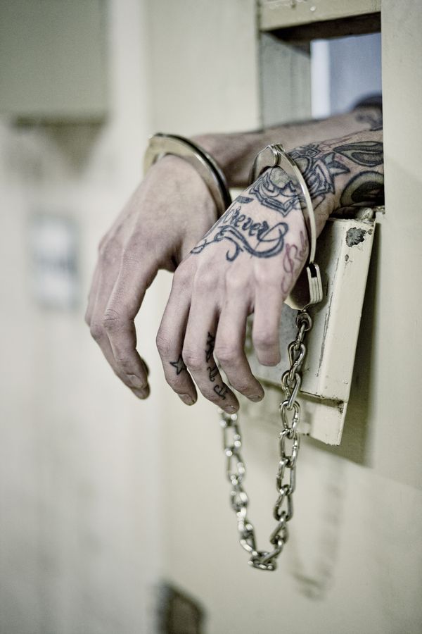 a man's hand holding onto a chain attached to a door handle with tattoos on it