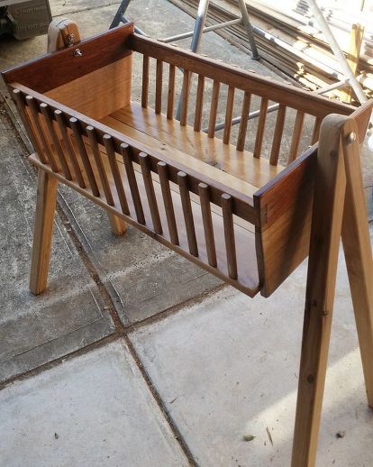 a wooden bench sitting on top of a cement floor next to a pile of wood