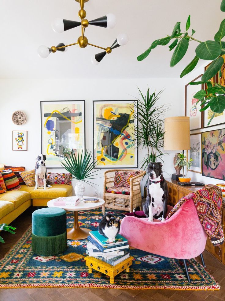 a living room filled with lots of furniture and paintings on the wall next to a yellow couch