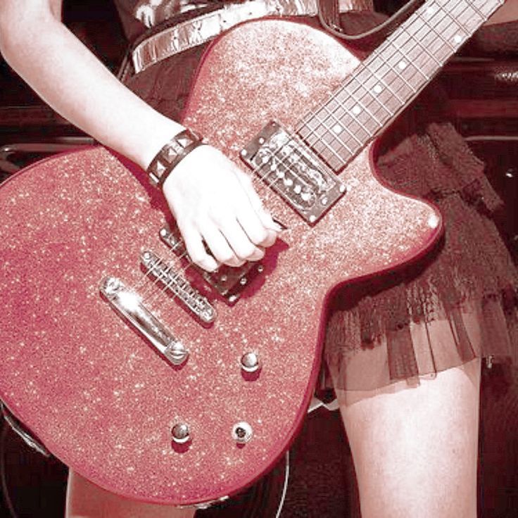 a woman holding a pink guitar in her hand