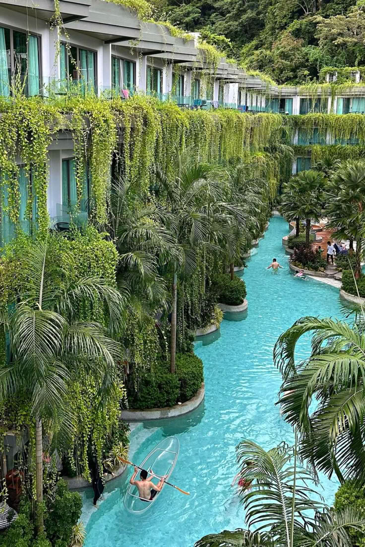 a man in a hammock is floating down a pool surrounded by palm trees