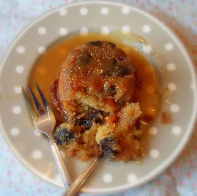 a white plate topped with a piece of cake next to a fork and spoon on top of a polka dot table cloth