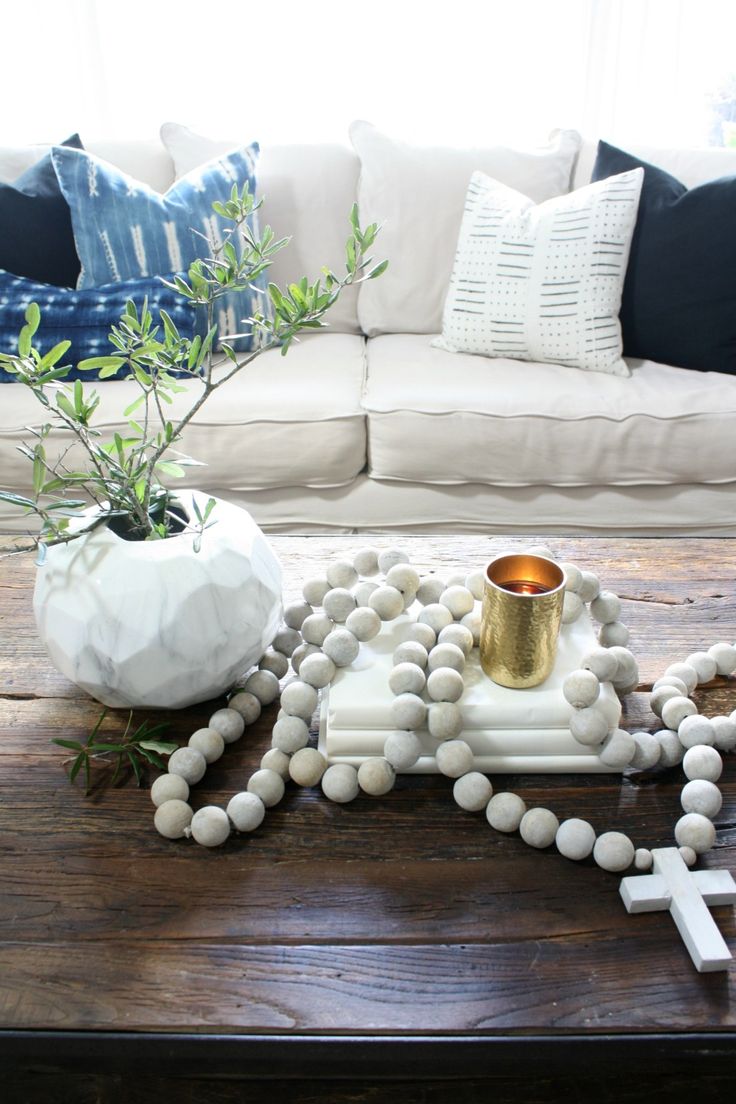 a wooden table topped with a cross, candle holder and beads on top of it