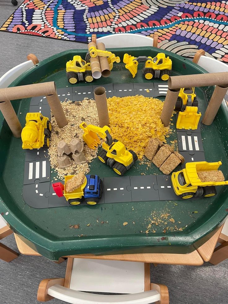 a green tray filled with construction toys on top of a wooden table next to a colorful rug