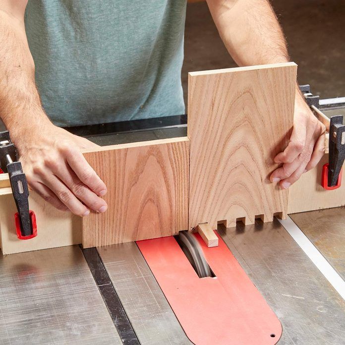 a man working on a piece of wood with a planer and tools attached to it