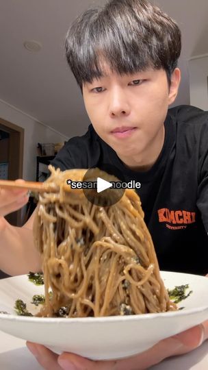 a man holding a plate of noodles with chopsticks