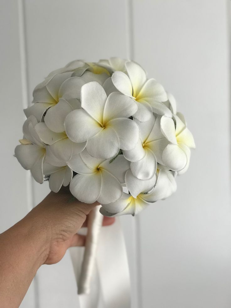 a person holding a bouquet of white and yellow flowers