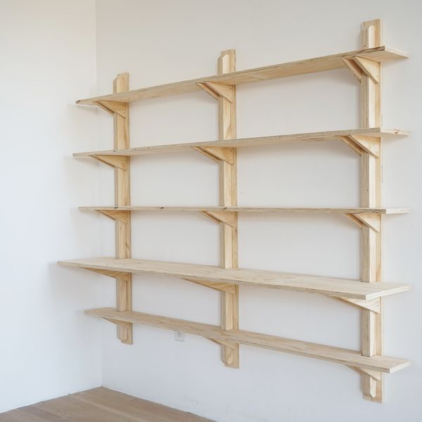 a wooden shelf sitting on top of a white wall next to a wood flooring