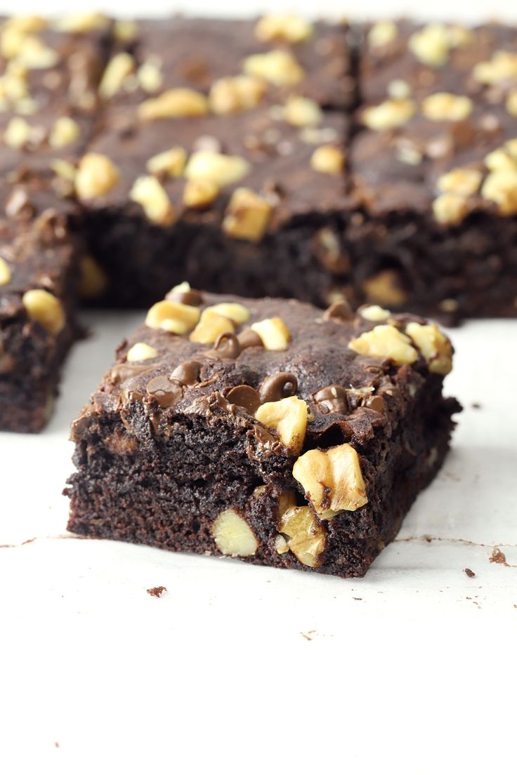 chocolate brownies with walnuts on top cut into squares and placed on a white surface