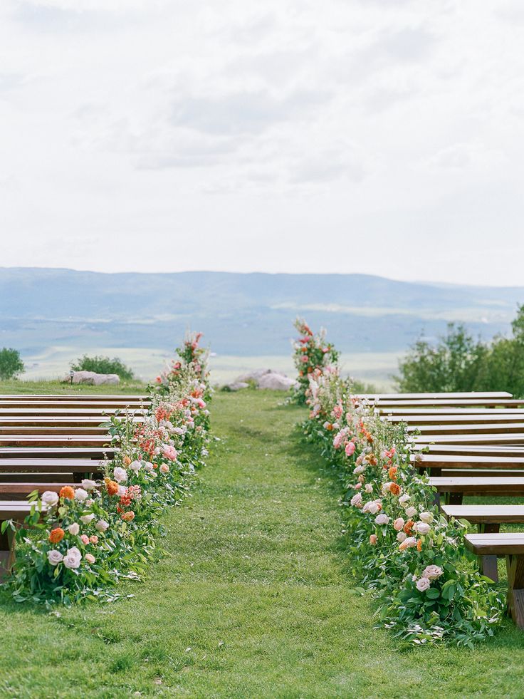 rows of wooden benches lined with flowers in the grass