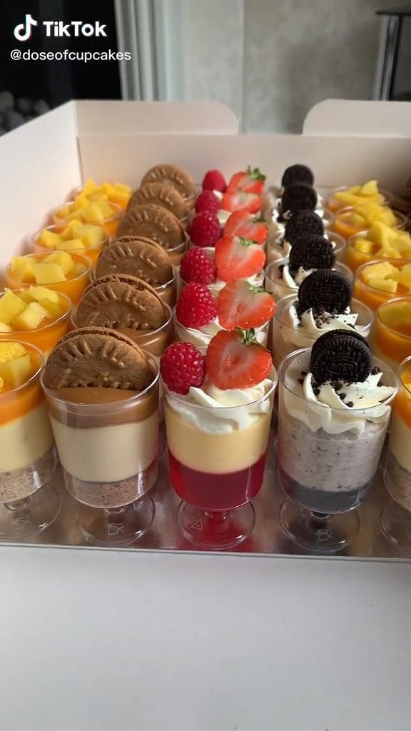 an assortment of desserts in small cups on a tray