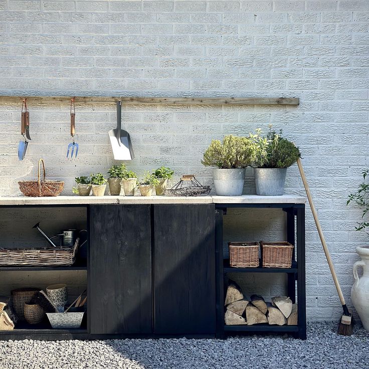 an outdoor kitchen with potted plants on the counter and pots hanging from hooks above it