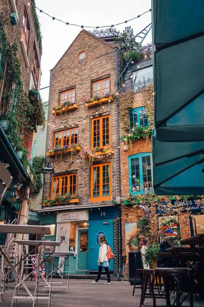 a woman walking down the street in front of an old brick building with many windows