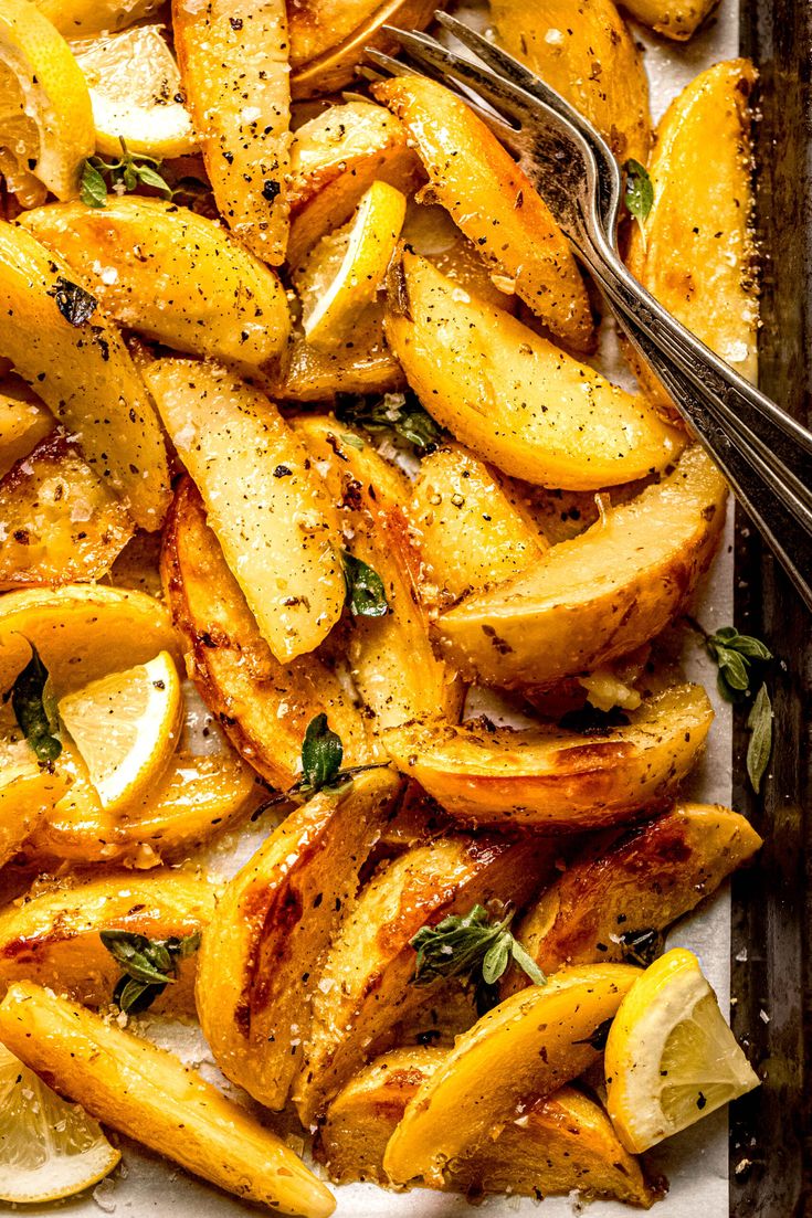 baked potatoes with herbs and lemons on a baking sheet, ready to be eaten