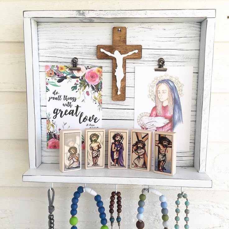 a cross and some beads are hanging on a shelf with other rosarys in front of it