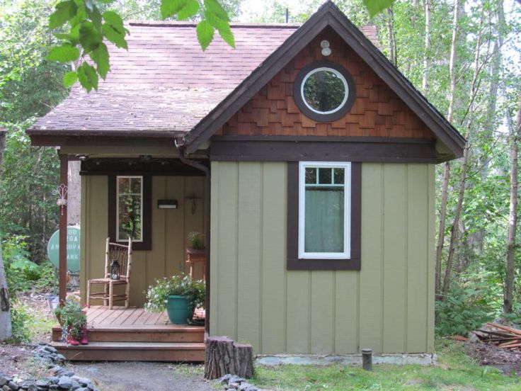 a small house in the woods with a porch and steps leading up to it's entrance