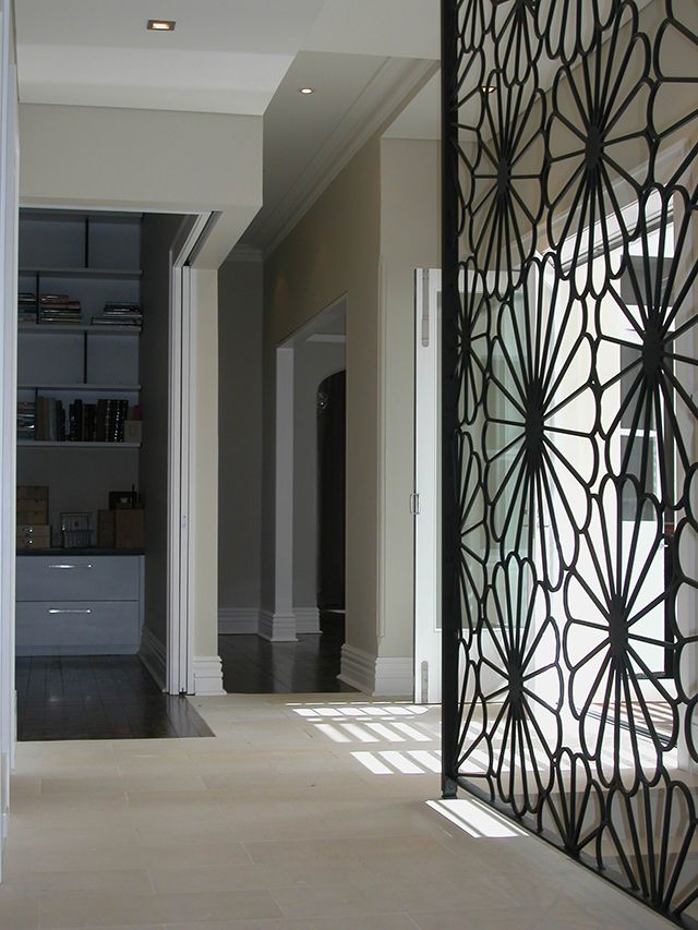 the interior of a house with white walls and black metal screens on the door,