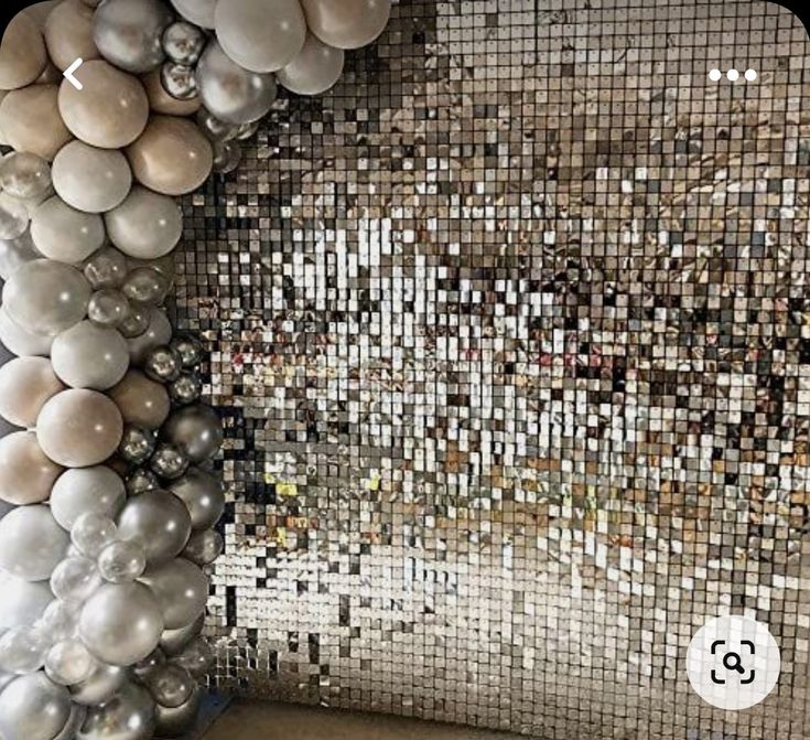 a mosaic wall with silver and white balls hanging from it's centerpieces