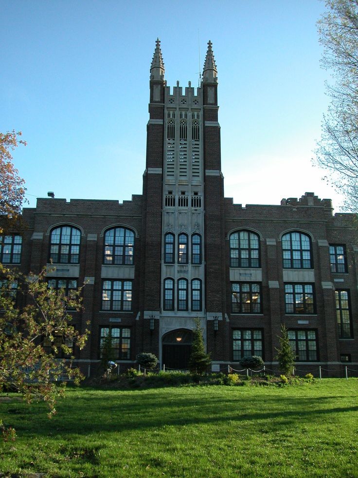 a large building with many windows on the front and side of it, surrounded by green grass