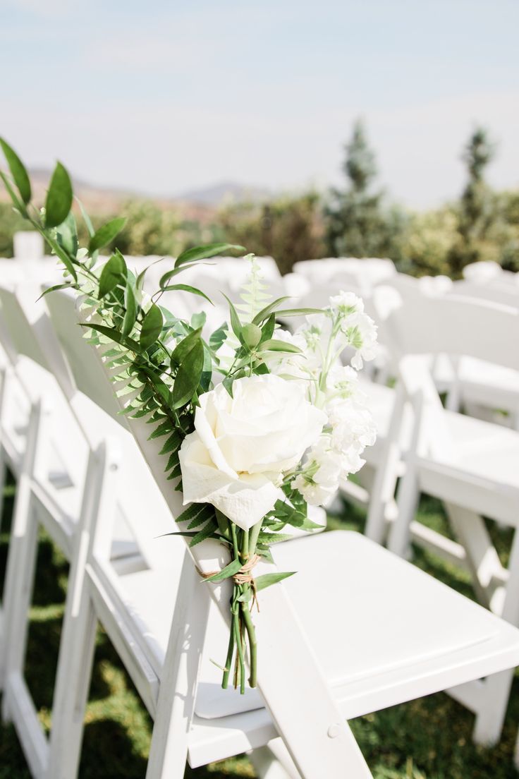 a bouquet of flowers sitting on top of a white chair in front of rows of chairs