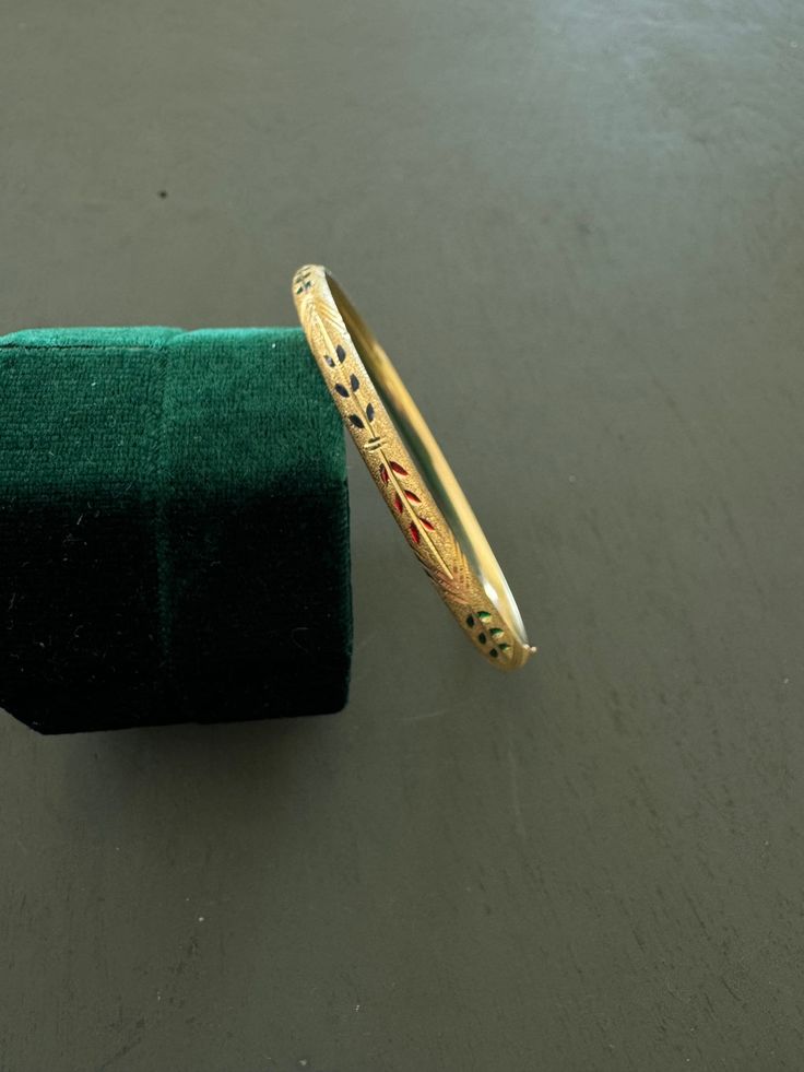 Beautiful vintage gold bangle bracelet - 14k yellow gold bracelet with sturdy hinge and well made locking mechanism.  This gold bracelet features a beautiful stipples texture with hand engraved details and enameled laurels of blue, green, and red.  Please note this item is vintage and may show signs of ware. It is in great condition and functions perfectly. Its is a lovely pieces to add to a jewelry collection or to wear alone as a quiet piece of luxury. Unmissable gold coloring and details make this piece quite elegant and noteworthy. Please see photos as they are part of description, and feel free to message if you have any questions! Thanks for looking! Locking Mechanism, Gold Bangle Bracelet, Yellow Gold Bracelet, Gold Bangle, Stippling, Green And Red, Hand Engraving, Gold Bangles, Bangle Bracelet