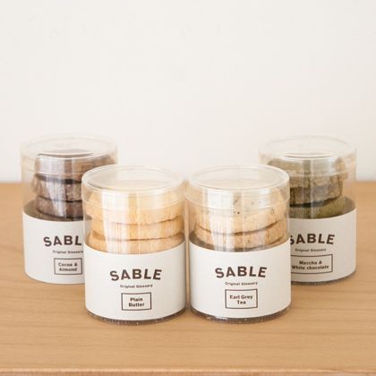 four jars filled with cookies sitting on top of a wooden table