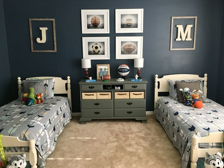 two twin beds in a room with blue walls and pictures on the wall above them