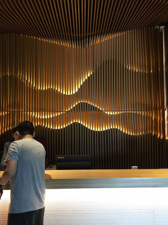 a man standing in front of a wooden wall next to a counter with lights on it